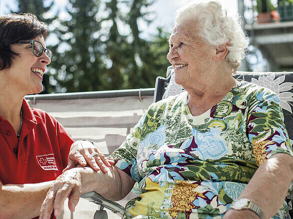Seniorin und Pflegefachkraft lachen gemeinsam. Szene DRK - Tagespflege